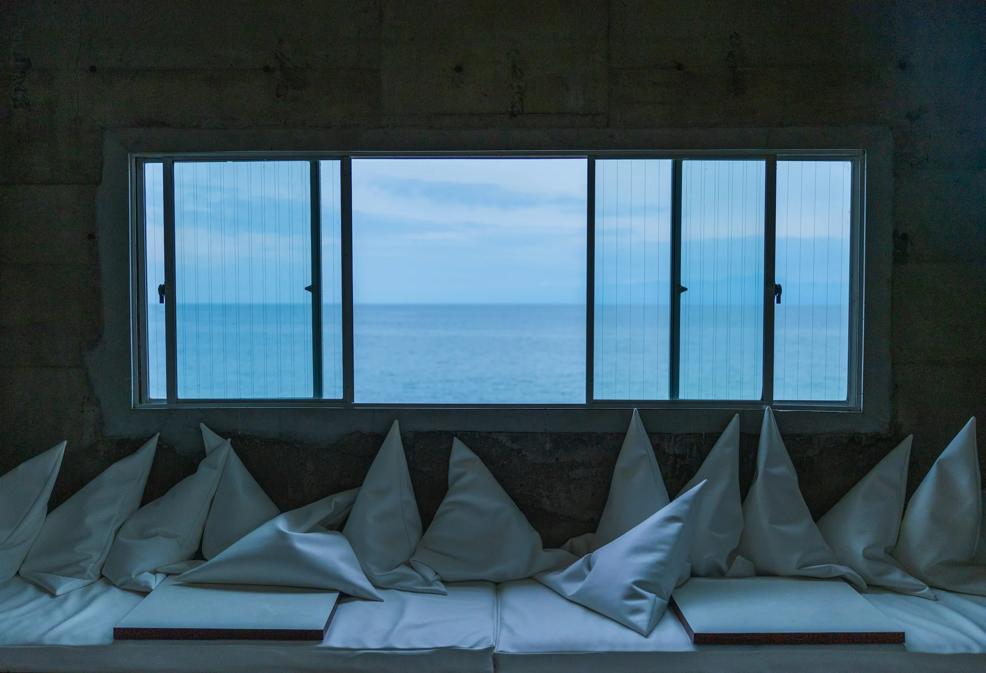 Soft white bedding beside a window over the sea