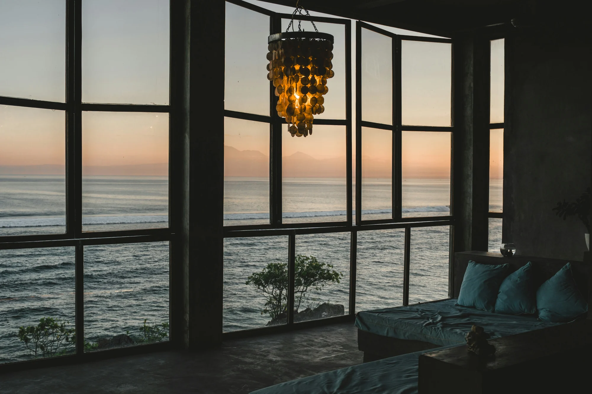 A modern living room opening to the ocean at sunset